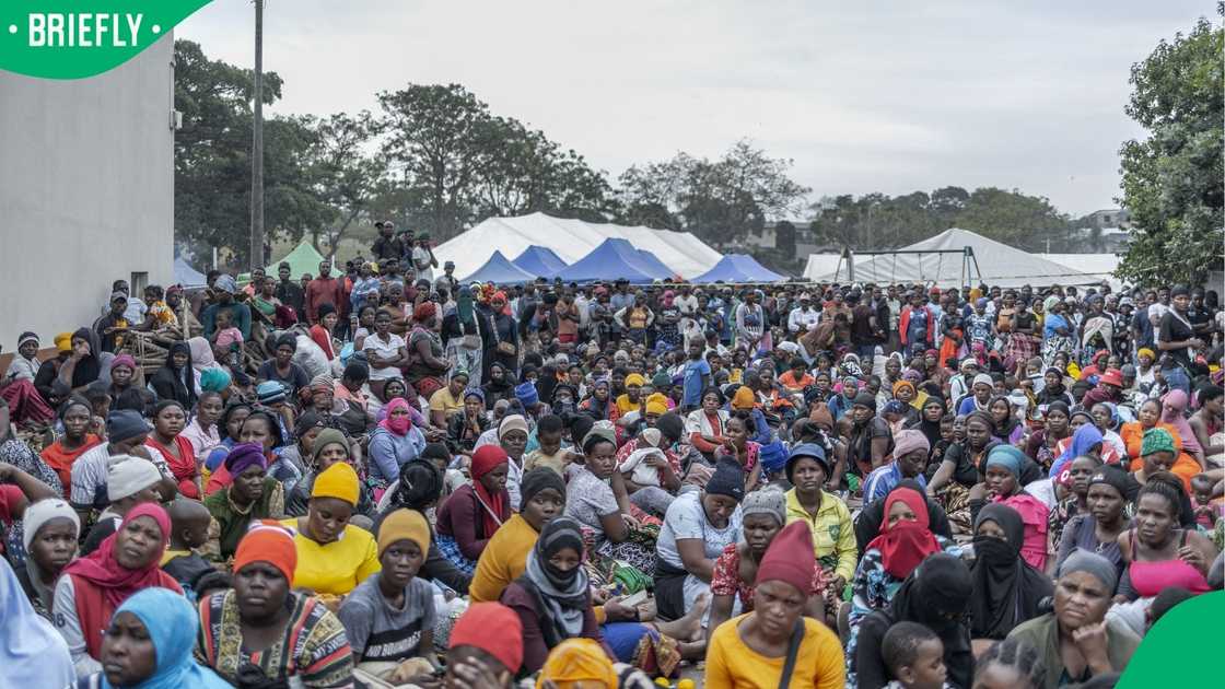 Hundreds of displaced women with children wait for local buses to be repatriated to Malawi