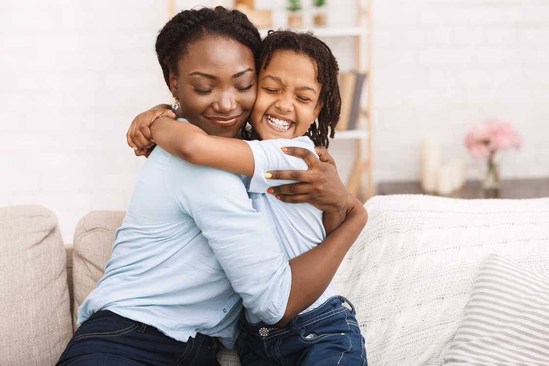 A woman and her daughter hugging with closed eyes, sitting together A woman and her daughter hugging with closed eyes, sitting together