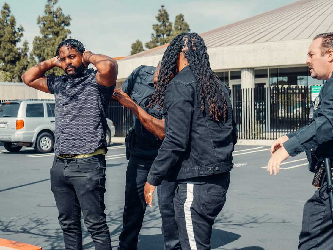 Officers escorts a man toward a patrol car outside. Officers escorts a man toward a patrol car outside.