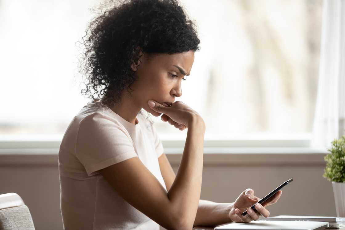 A disappointed woman looking at smartphone screen thinking