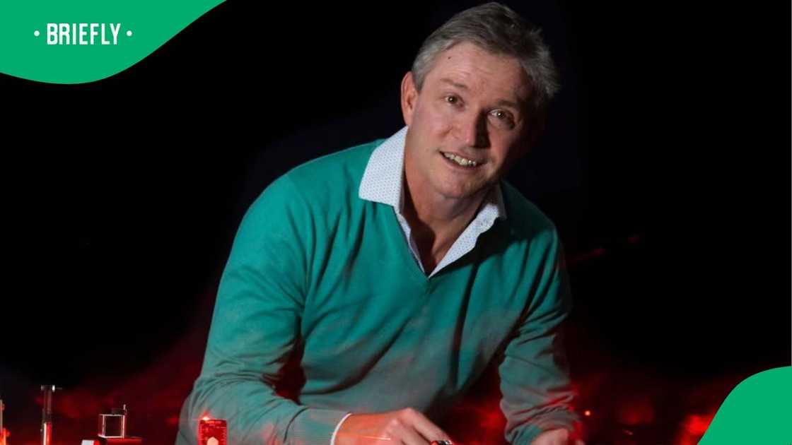 Andrew smiled slightly as he demonstrated an experiment surrounded by glowing red lights Andrew smiled slightly as he demonstrated an experiment surrounded by glowing red lights