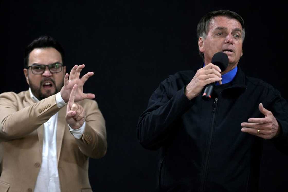 President Jair Bolsonaro (R) gives a speech in Brazil on July 15 2022, next to a sign language translator (L)