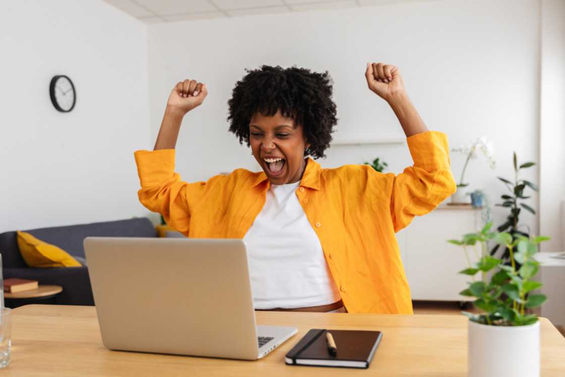 A woman celebrating winning the lotto while viewing her laptop.