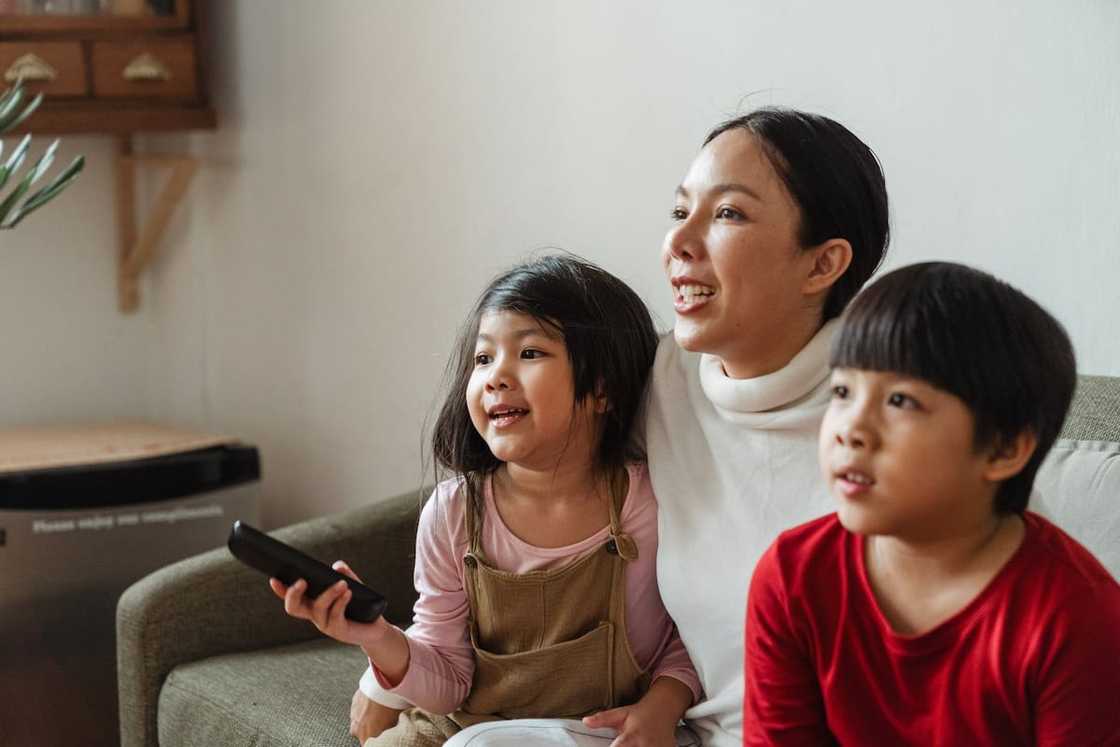 Kids with their mother watching the TV on the weekend