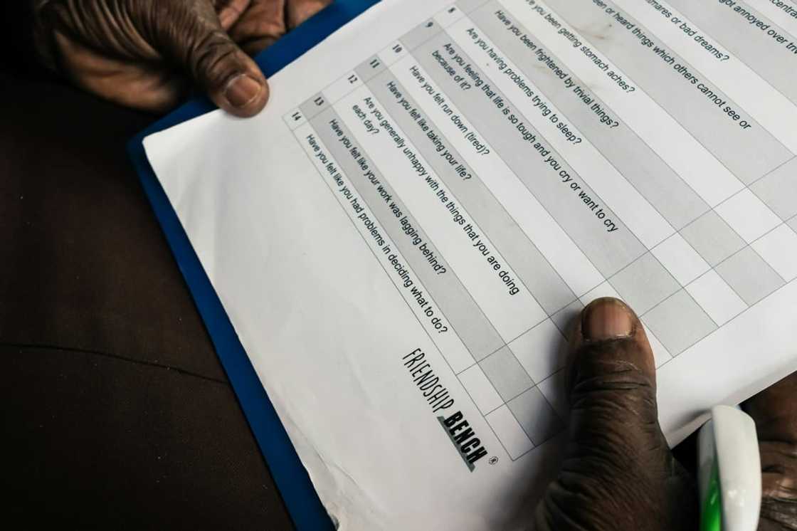 Counsellor Shery Ziwakayi reads her guidance notes as she sits on a bench waiting for a client. Zimbabwean doctor Dixon Chibanda created the Friendship Bench project, a novel way of providing desperately needed, yet free mental health therapy using elderly lay health workers referred to as grandmas.