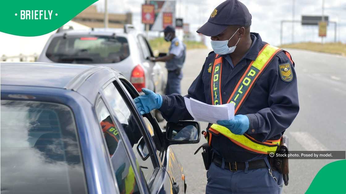 An officer in a high-visibility vest gestured toward a vehicle's open window during a routine traffic stop on a multi-lane highway An officer in a high-visibility vest gestured toward a vehicle's open window during a routine traffic stop on a multi-lane highway