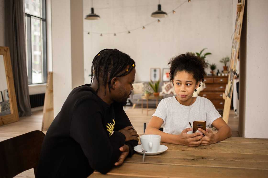 A father and daughter sitting at a table while talking.