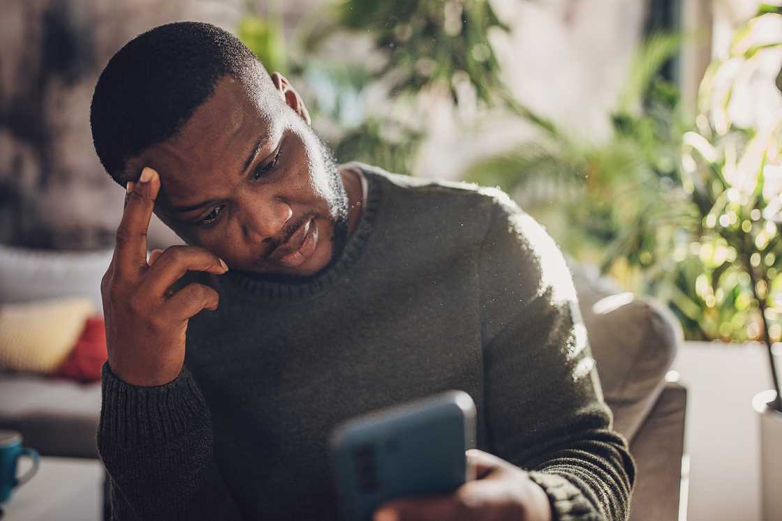 An annoyed man looking at his phone.