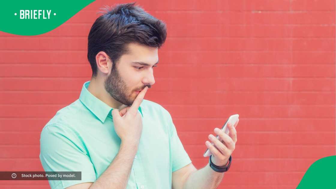 A man looking at his phone in confusion.