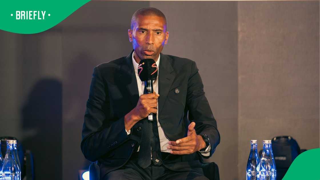 Image of Orlando Pirates head coach Abdeslam Ouaddou wearing suit holding microphone Image of Orlando Pirates head coach Abdeslam Ouaddou wearing suit holding microphone