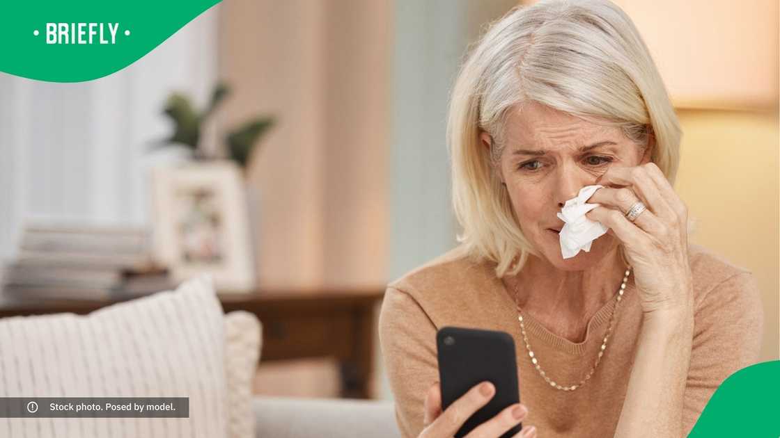 A woman crying while looking at her phone.