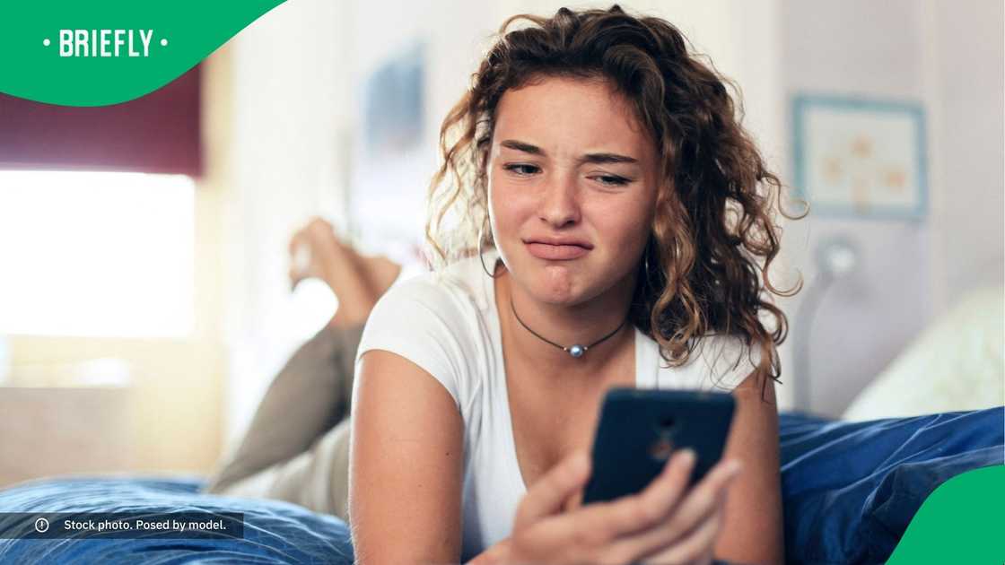 A teen looking at her phone in disgust.