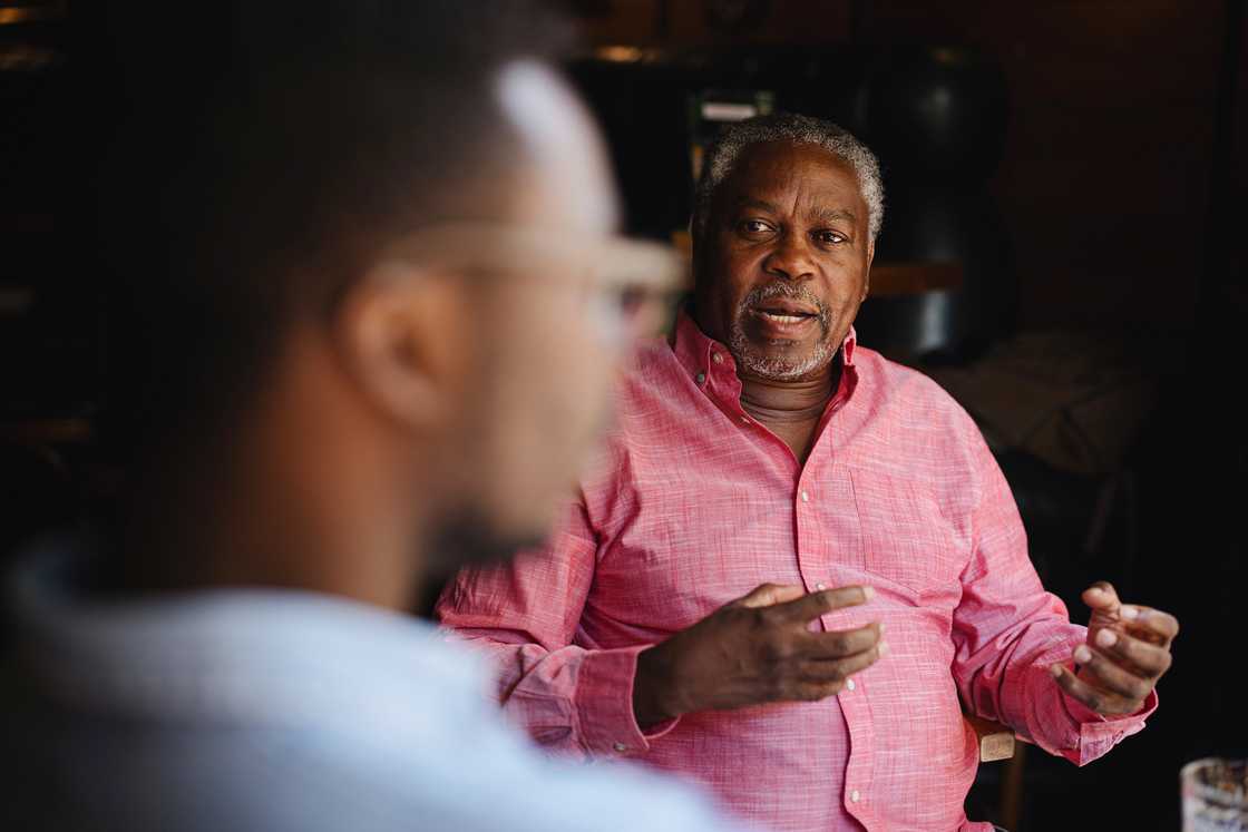 Older person gestures while speaking to someone indoors. Older person gestures while speaking to someone indoors.