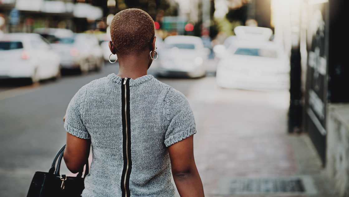 A rear view shot of a young woman walking outdoors in the city