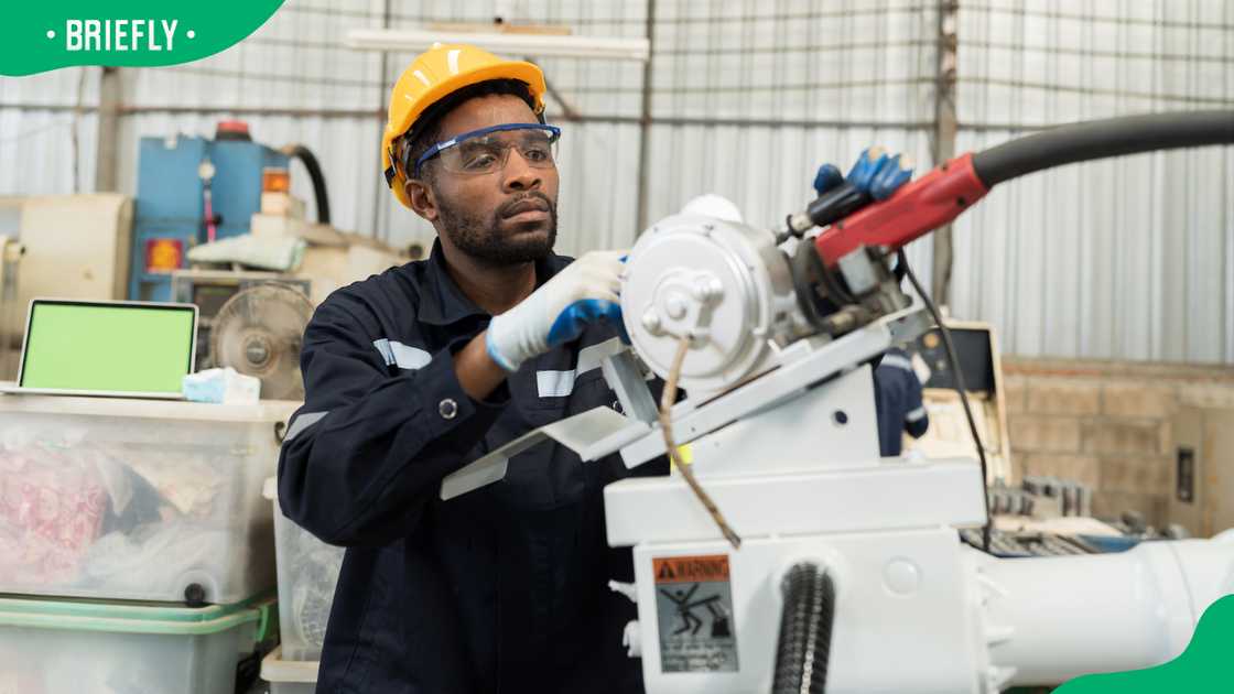 A male engineer repairing an automatic robotic arm machine. A male engineer repairing an automatic robotic arm machine.