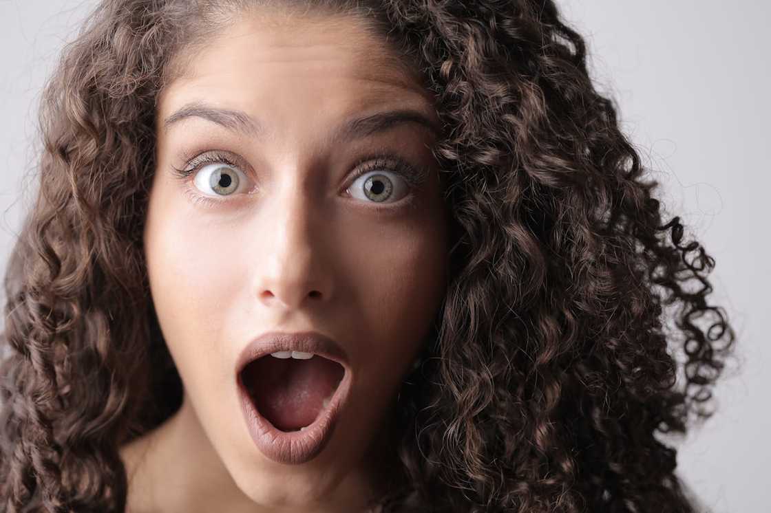 Close-up of a shocked woman with wide eyes and an open mouth.