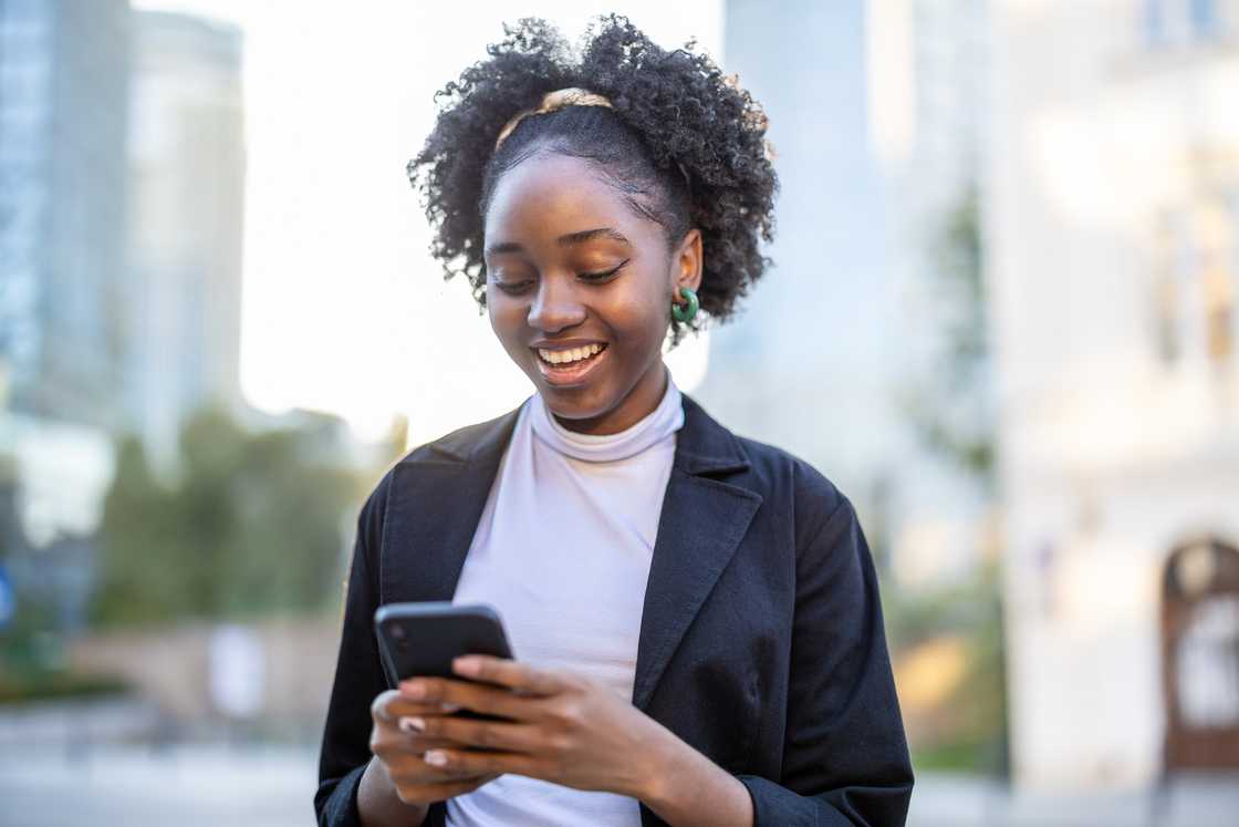 A woman smiling at her phone.