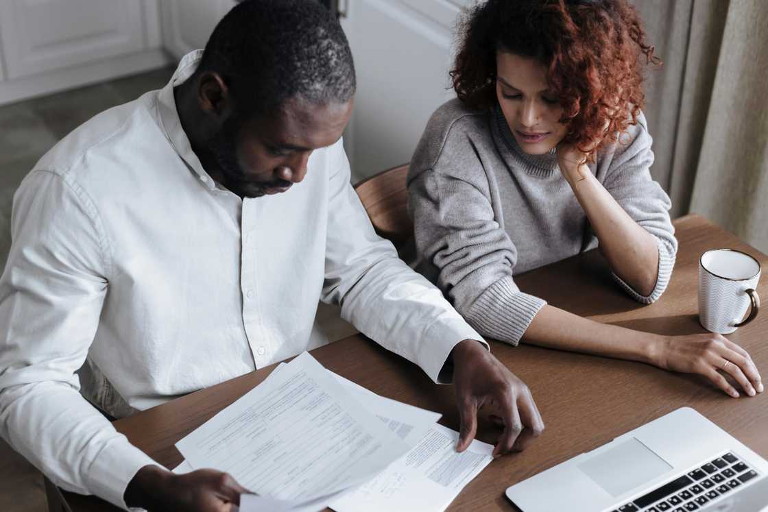 A couple reviewing documents together at a wooden table. A couple reviewing documents together at a wooden table.