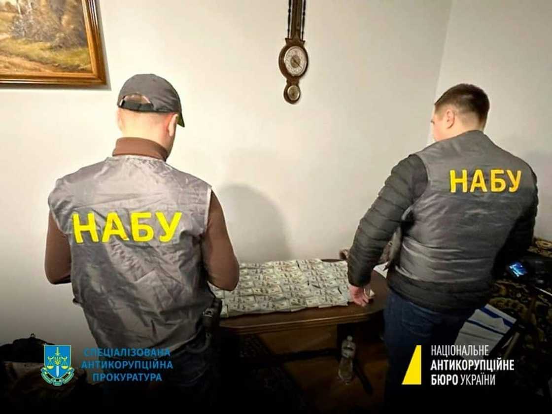 A handout photograph by the National Anti-Corruption Bureau of Ukraine shows NABU staff members next to seized money