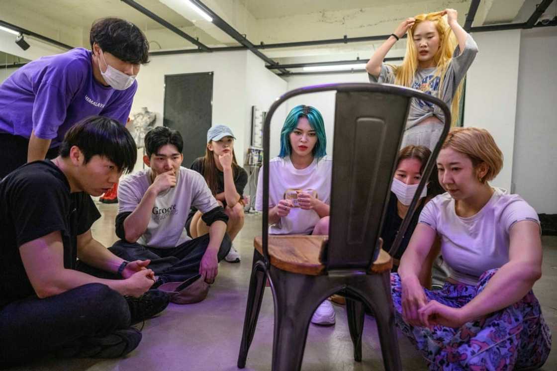 K-pop star AleXa (C) and her dance crew watch mobile phone footage of their rehearsal