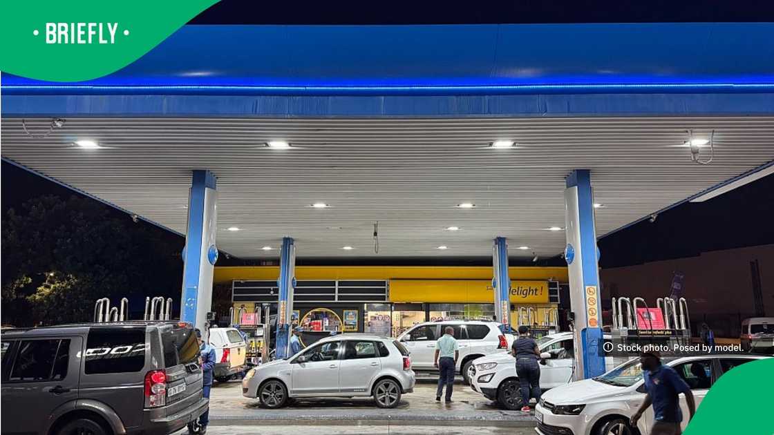 Petrol attendants and motorists moved around the illuminated forecourt as vehicles occupied the service bays Petrol attendants and motorists moved around the illuminated forecourt as vehicles occupied the service bays