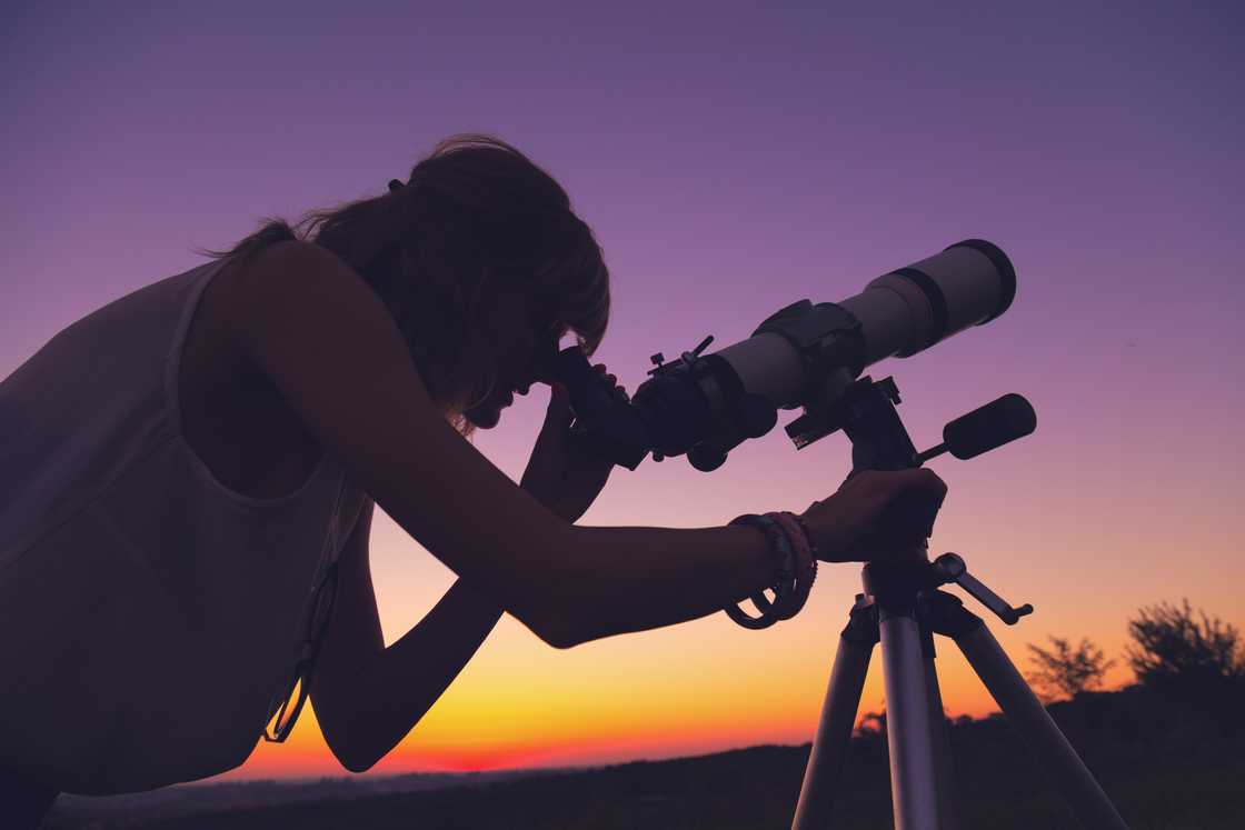 A woman looking through a telescope. A woman looking through a telescope.