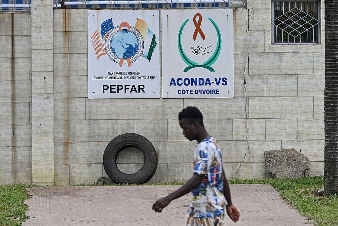 A pedestrian walks past a PEPFAR sign in Abidjan on July 12, 2025