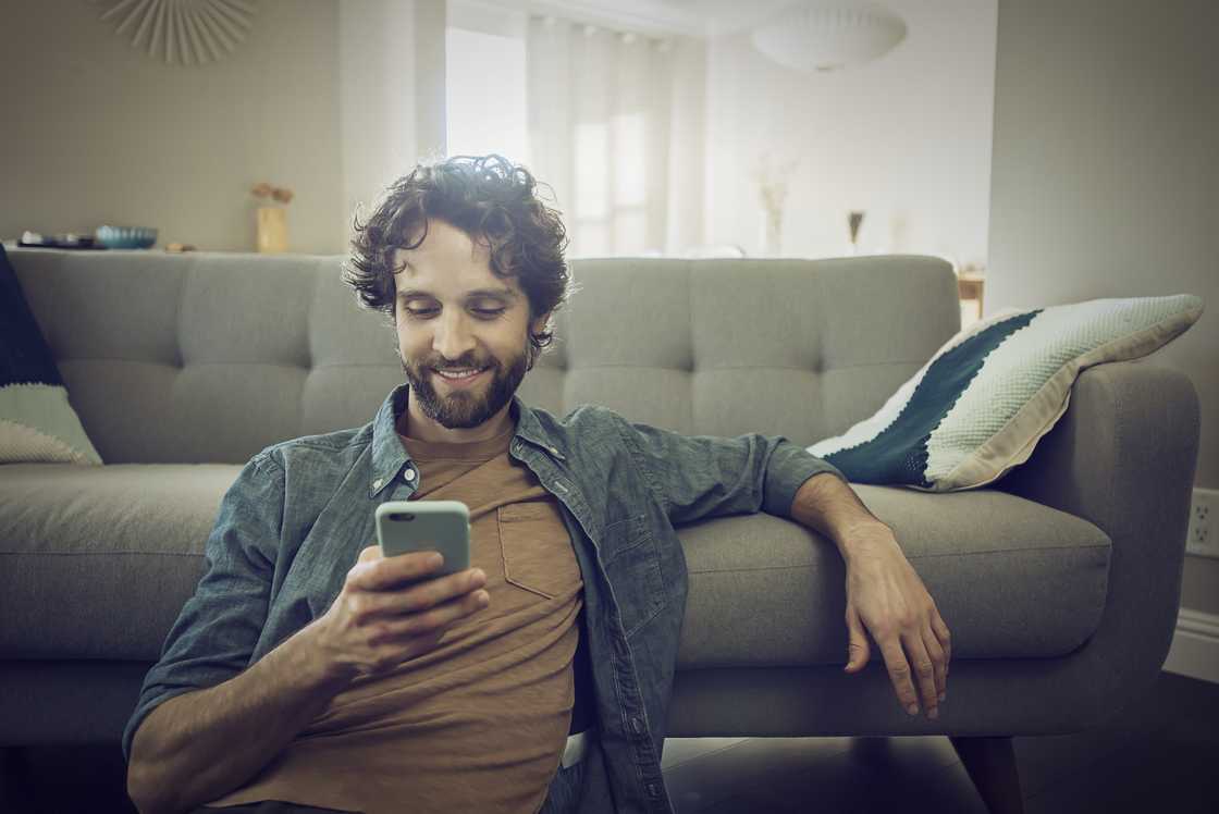 A man smiling at his phone. A man smiling at his phone.