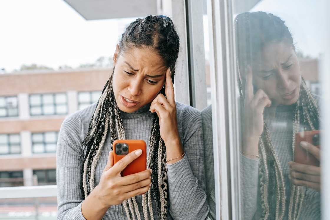 A young woman staring at her phone in shock.