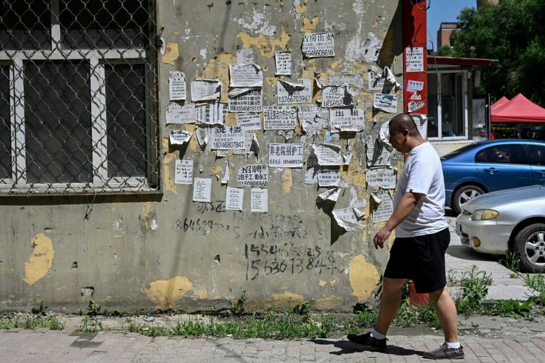 A man walks past home rental advertisements in a residential compound in Hegang city in northeastern China's Heilongjiang province