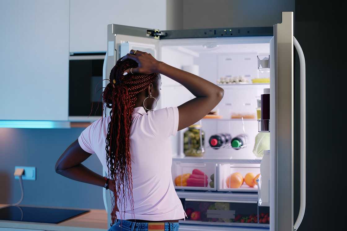 A woman is looking at food in a fridge
