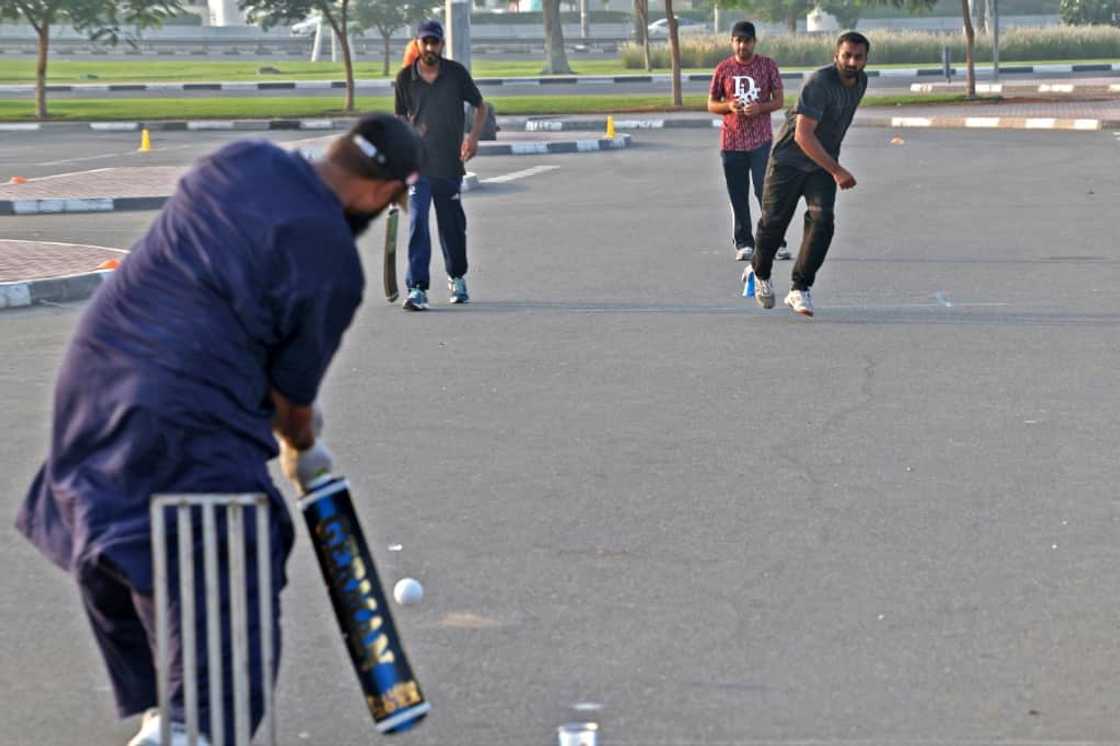 Expatriate workers play cricket in a parking lot in the Gulf emirate of Dubai