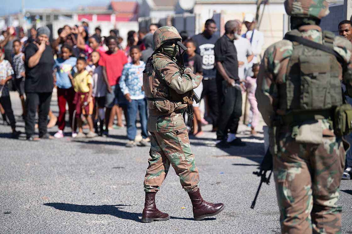 Residents watch soldiers of the South African National Defence Force (SANDF) on a patrol as part of Operation Prosper in Mitchells Plain, near Cape Town, on April 1, 2026