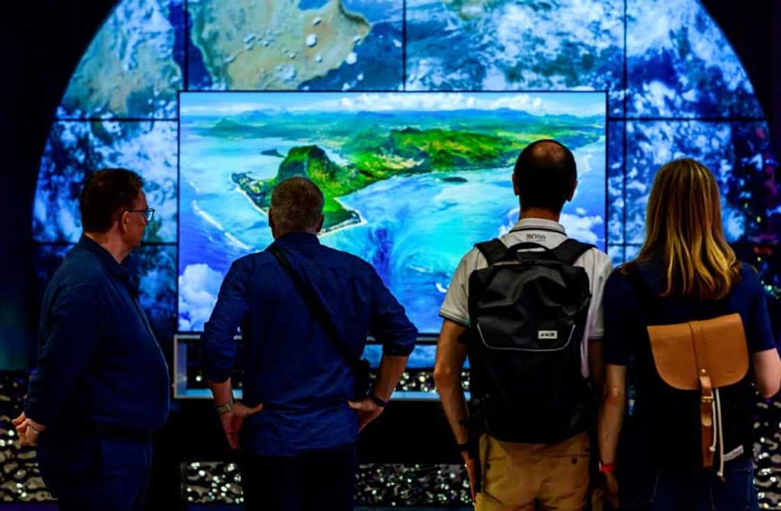 Visitors contemplate an 8K TV at the stand of South Korean consumer goods giant LG at the tech fair -- motto this year "energy efficiency"