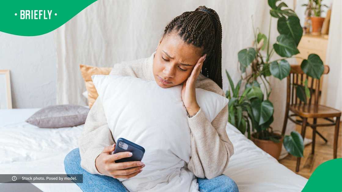 A sad woman looking at her phone. A sad woman looking at her phone.