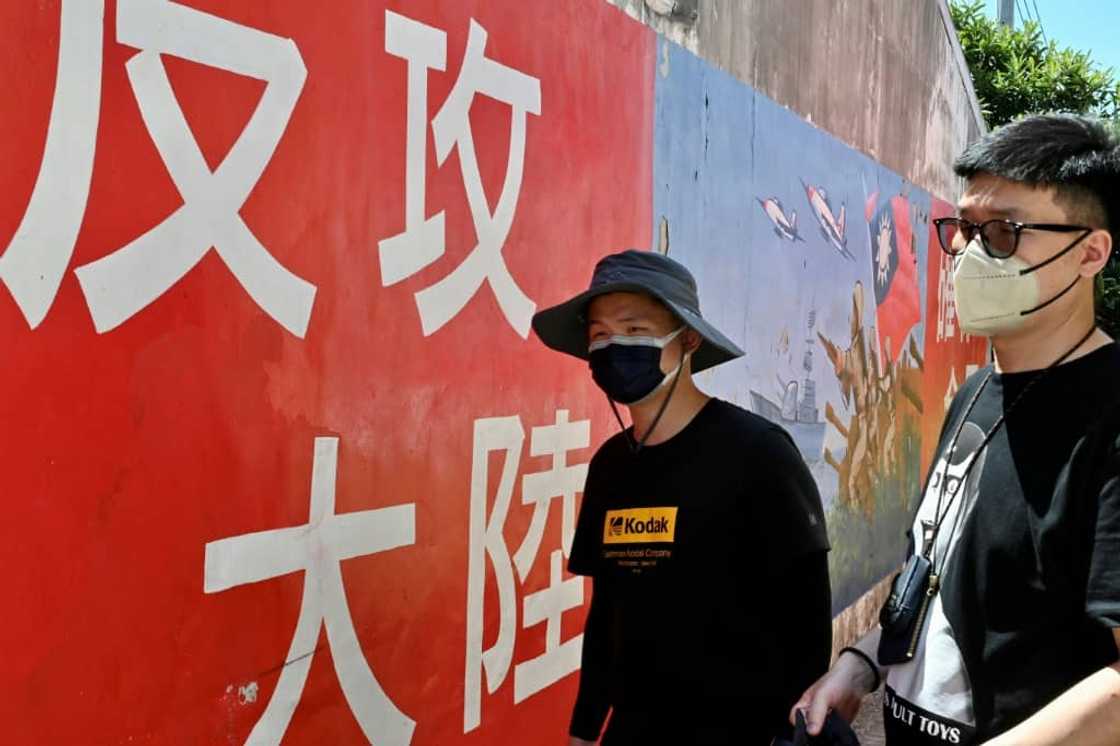 Tourists on Taiwan's Kinmen islands walk past a mural with a slogan that reads 'seize mainland China' Tourists on Taiwan's Kinmen islands walk past a mural with a slogan that reads 'seize mainland China'
