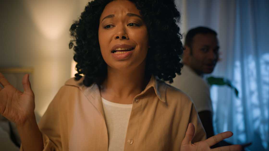 Husband and wife quarrelling while sitting apart on bed at night