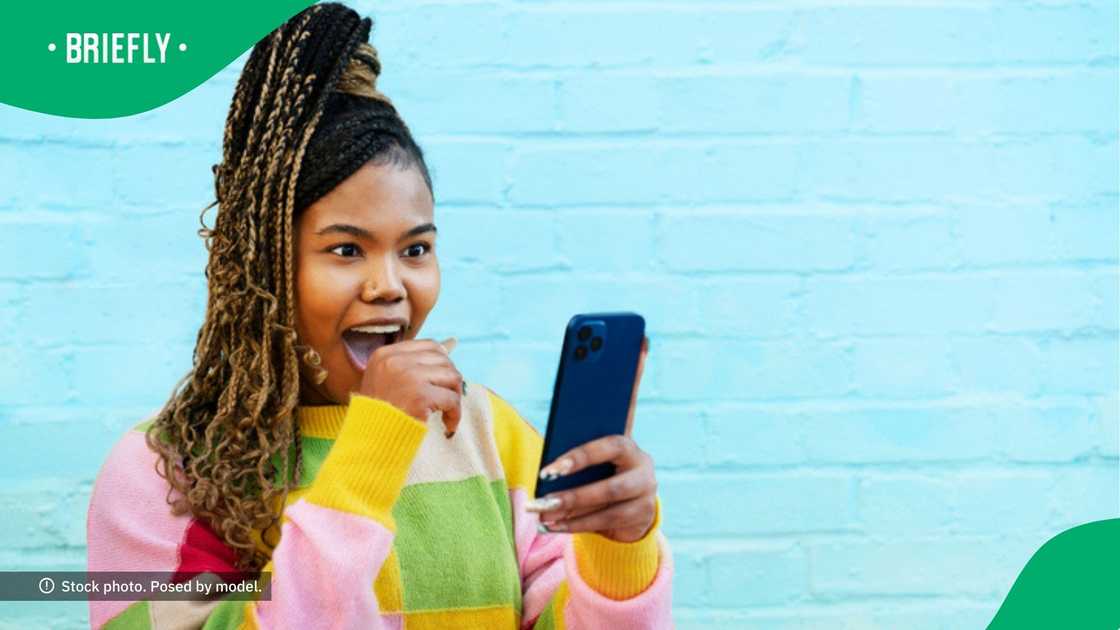 A woman stared at her phone in an image, looking stunned and amused. A woman stared at her phone in an image, looking stunned and amused.