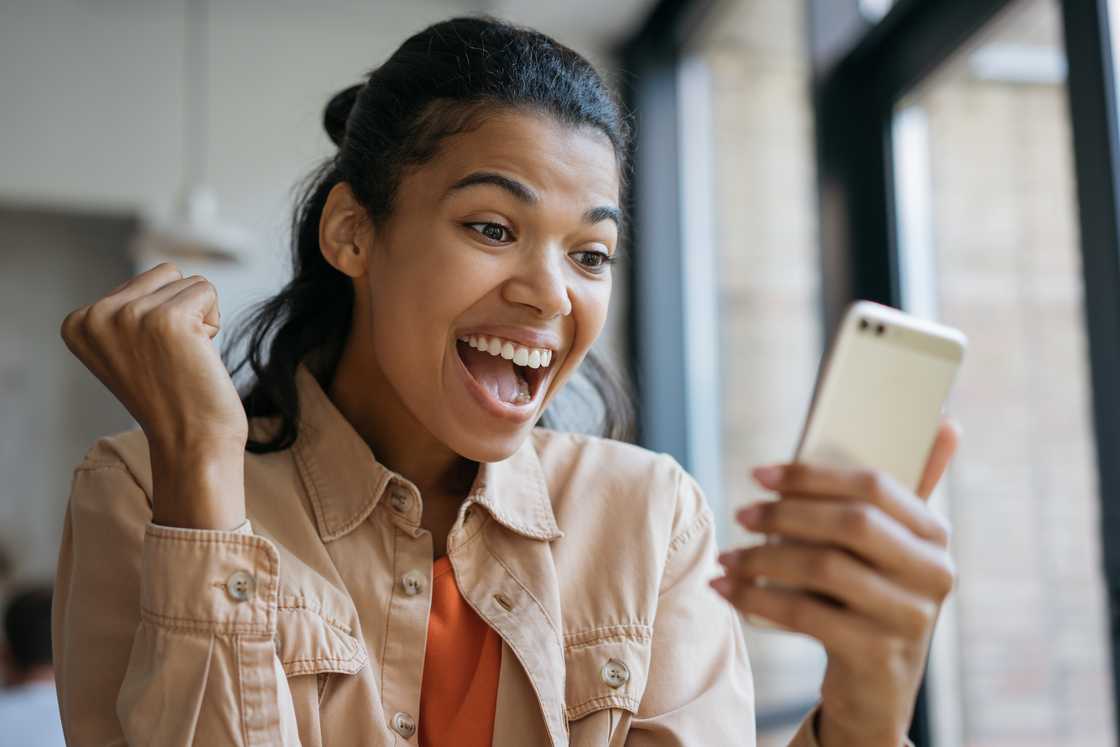 An excited woman looking at her phone.