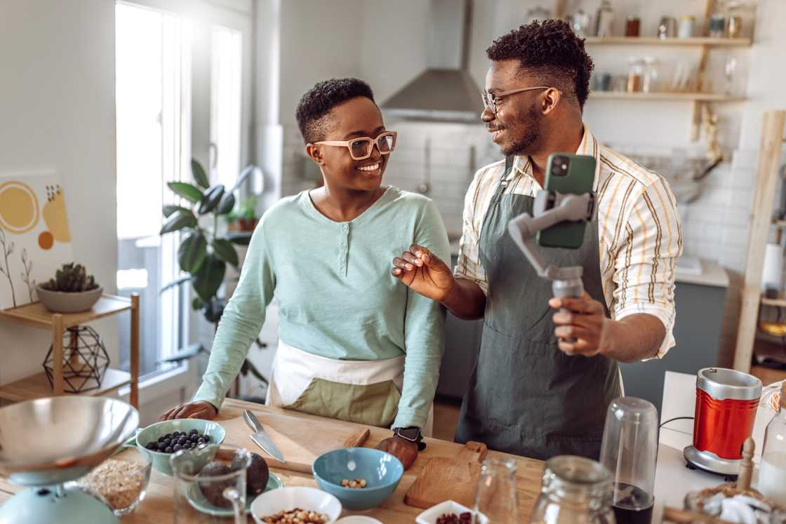 A young couple filming a kitchen challenge. A young couple filming a kitchen challenge.