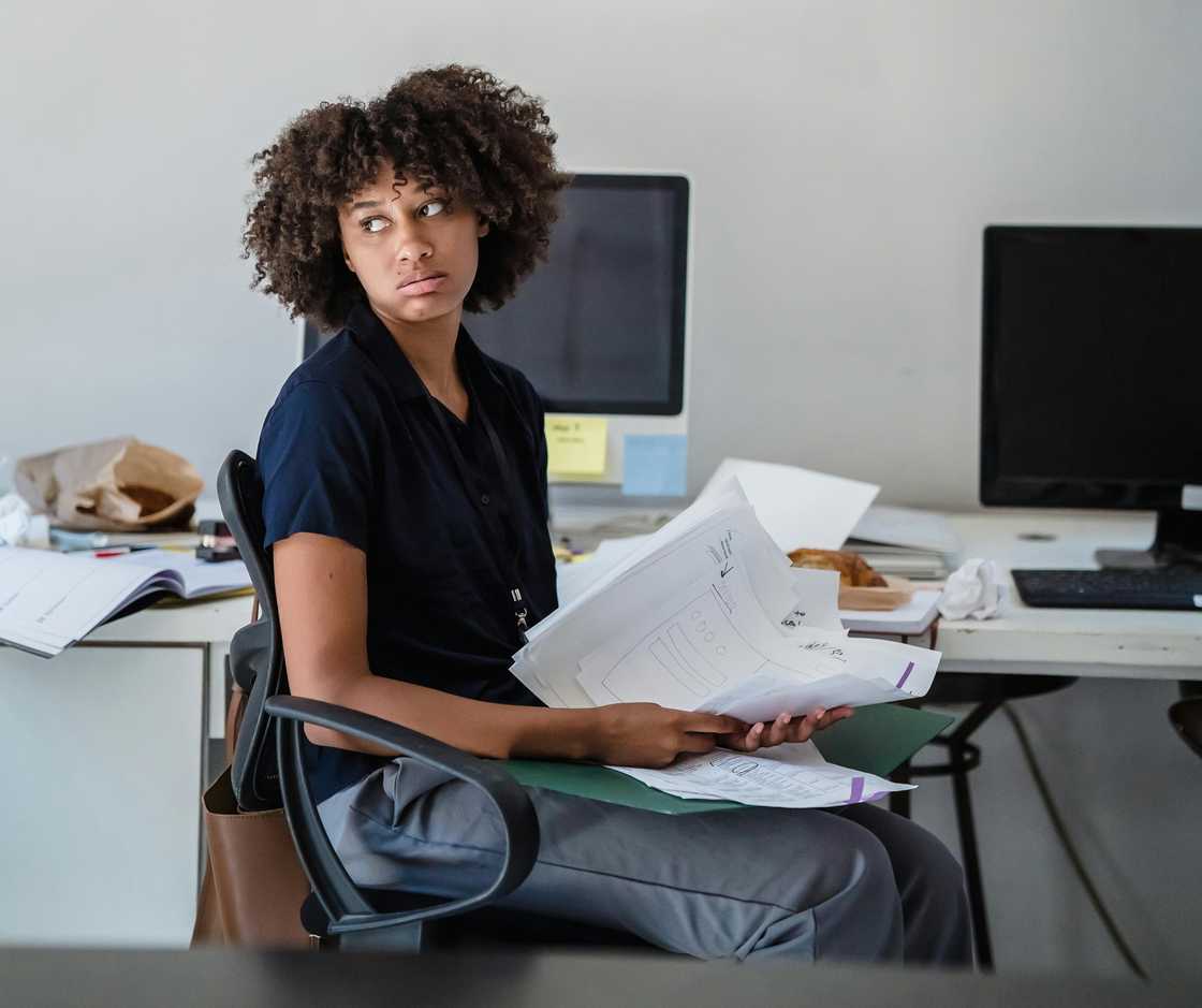 A tired woman in an office handling papers