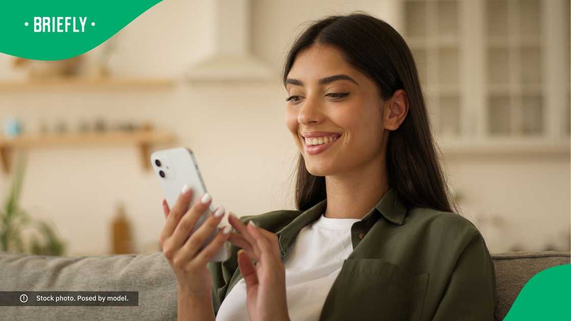 A woman smiling at her phone.