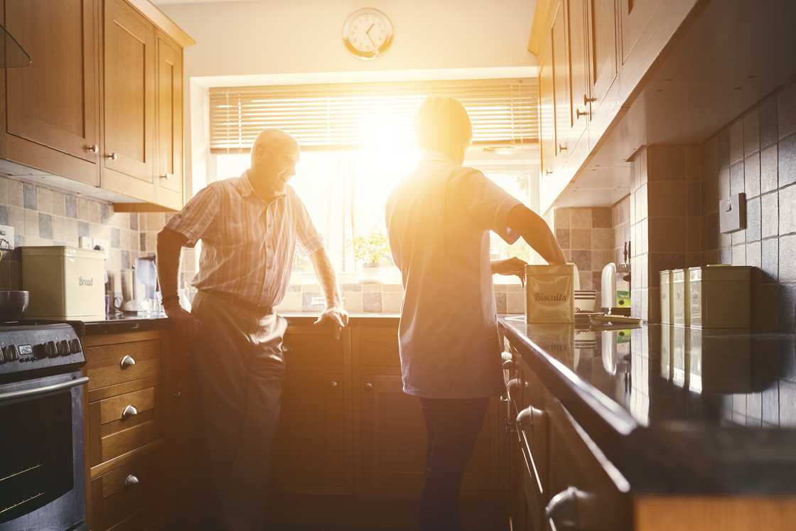 Two people stand in a warmly lit kitchen.