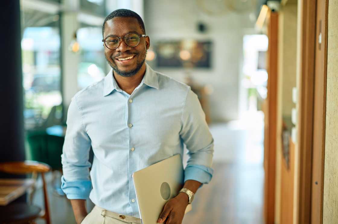 A happy programmer posing as he holds a laptop A happy programmer posing as he holds a laptop