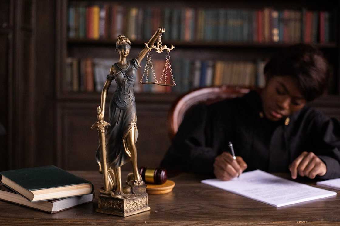 Lady Justice statue with a lawyer signing documents. Lady Justice statue with a lawyer signing documents.