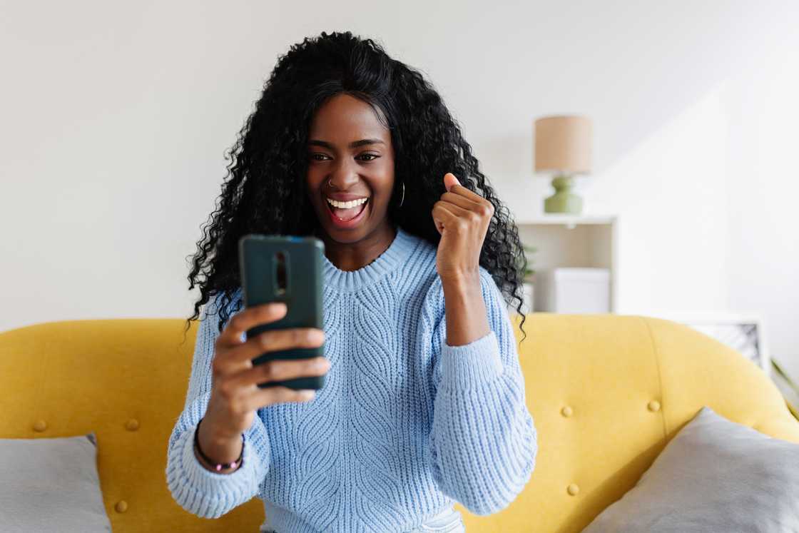 A woman happily looking at her phone.