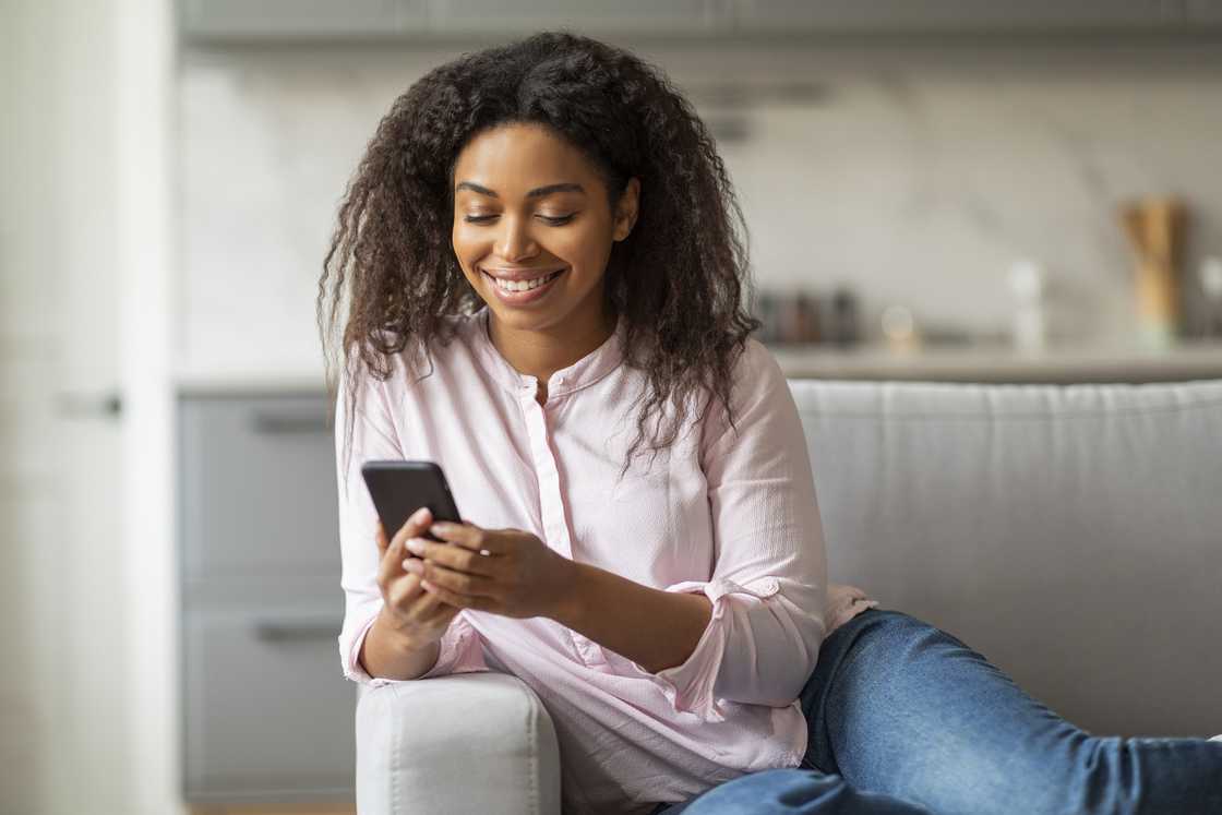 A woman smiling at her phone. A woman smiling at her phone.