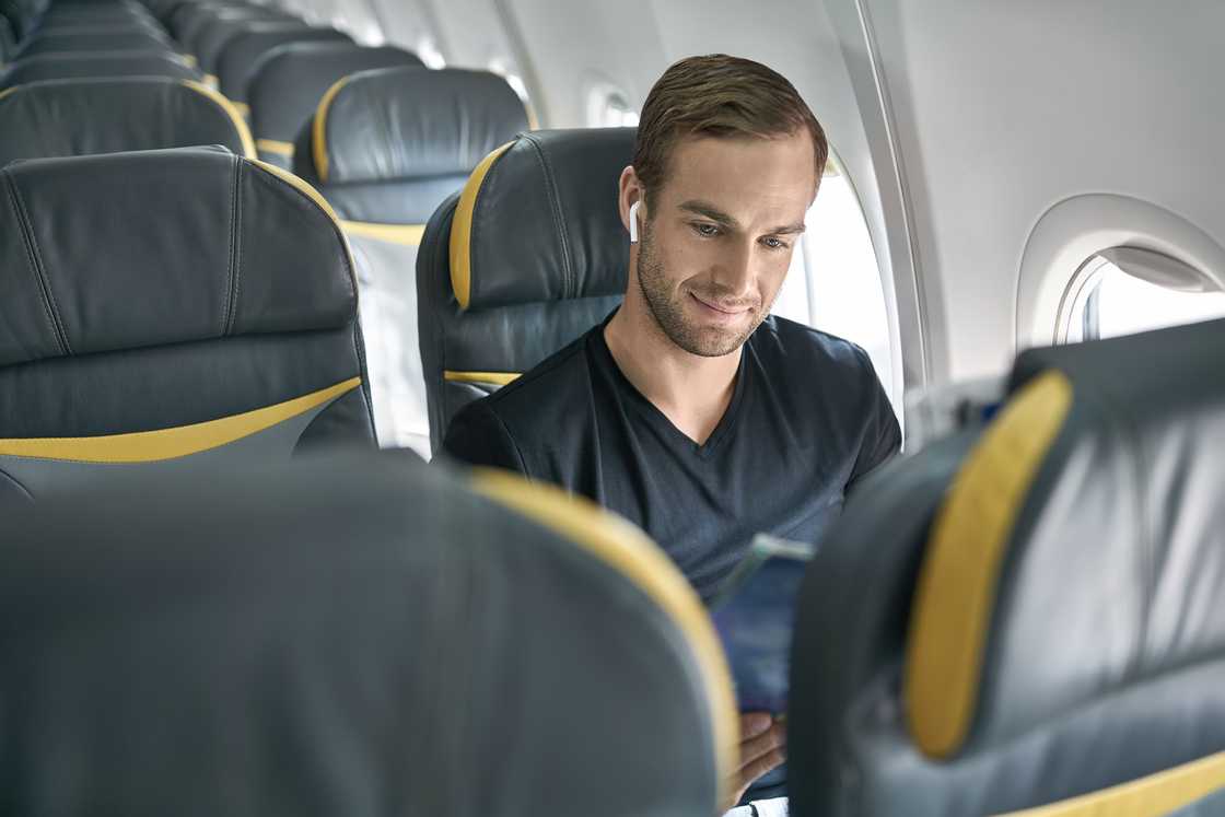 A man sitting in the aeroplane next to the window in the background of the empty seats