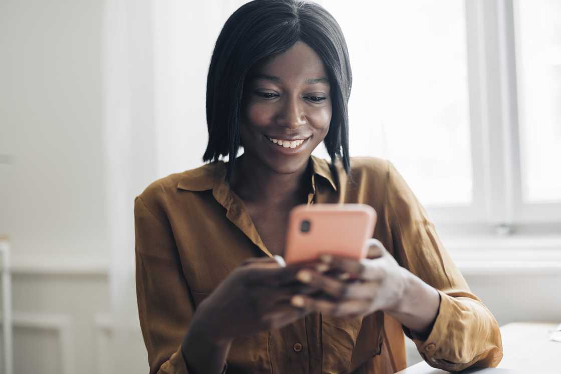 A woman smiling at her phone. A woman smiling at her phone.