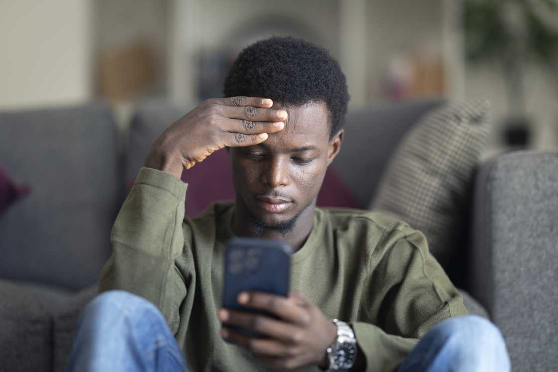 A person gripping his phone tightly after receiving some bad news.